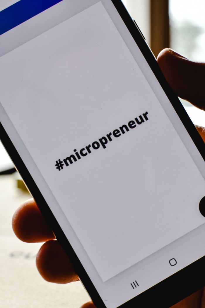 mission-img Close-up of a hand holding a smartphone with the hashtag #micropreneur on screen, symbolizing entrepreneurship.